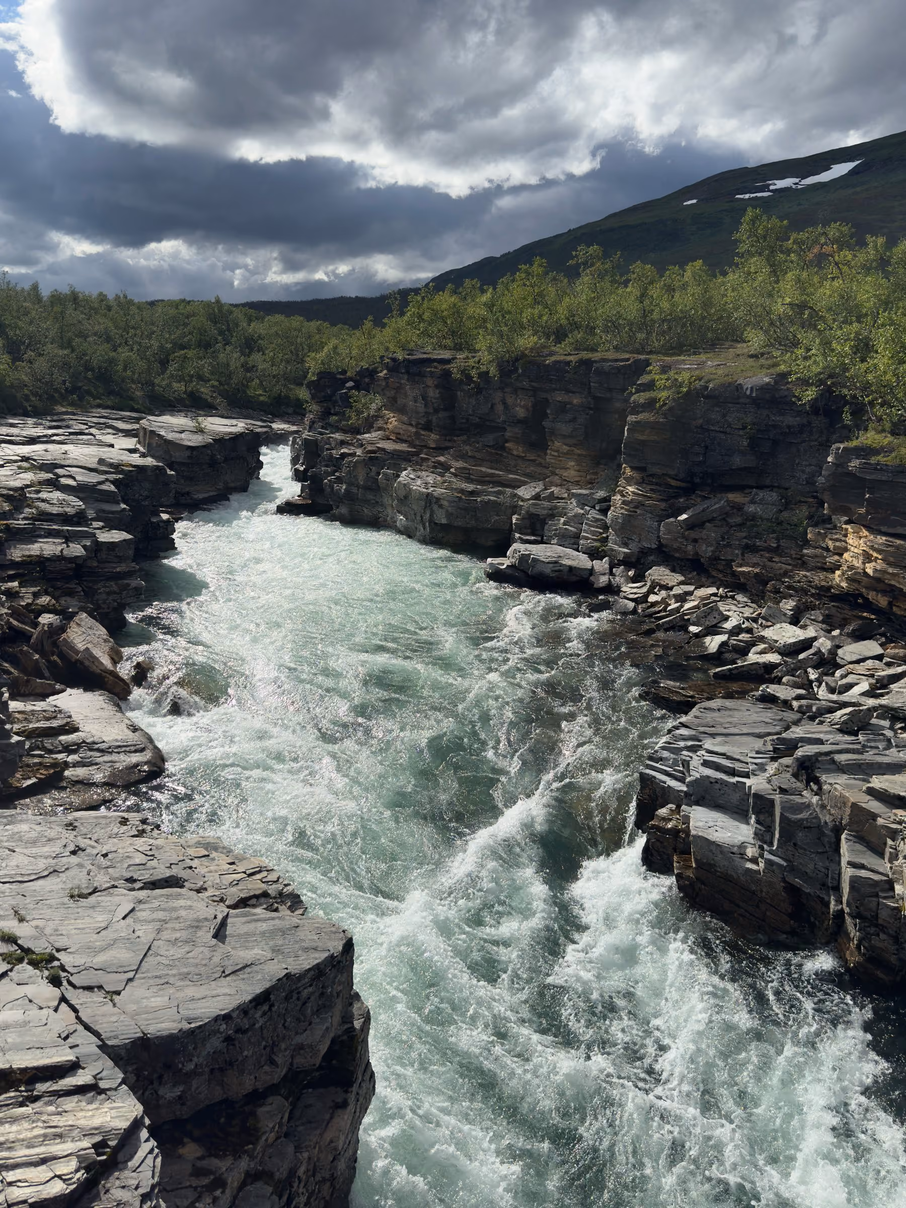 Schmale Schlucht mit türkisem Fluss zwischen Birken