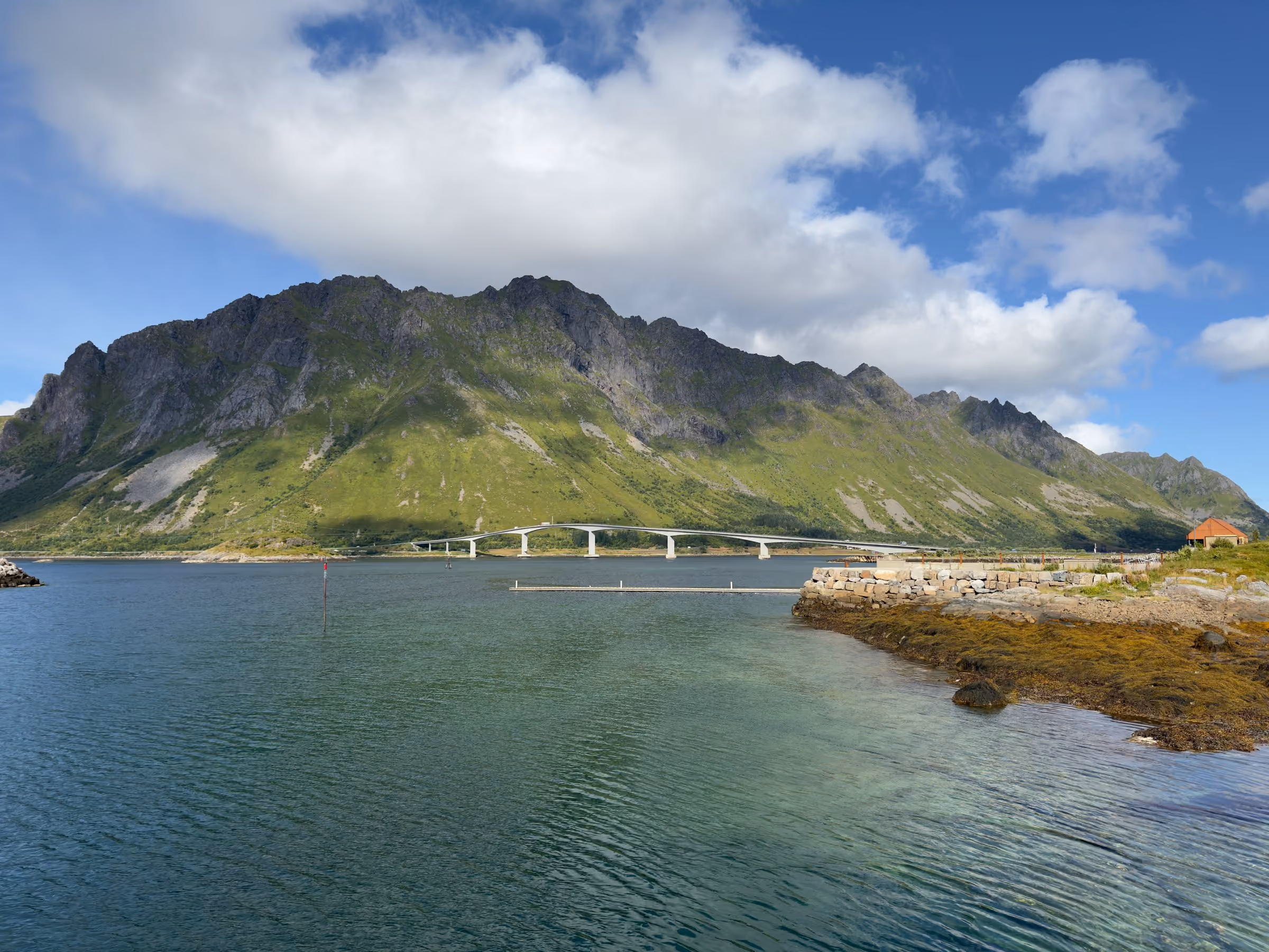 Brücke über einen Sund, dahinter ein steiler Bergrücken