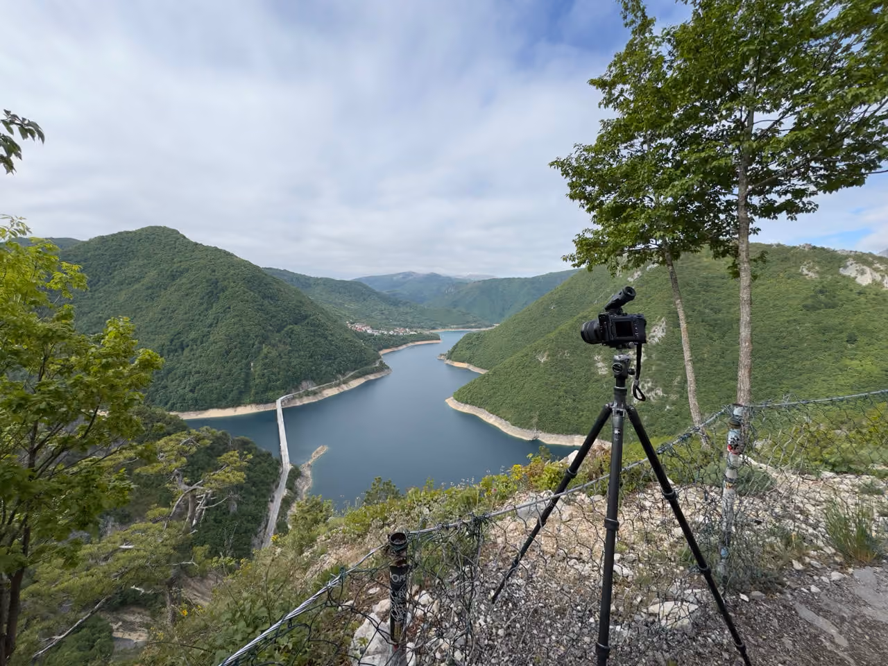 Der Stausee der Piva zwischen bewaldeten Hängen, im Vordergrund eine Kamera auf dem Stativ